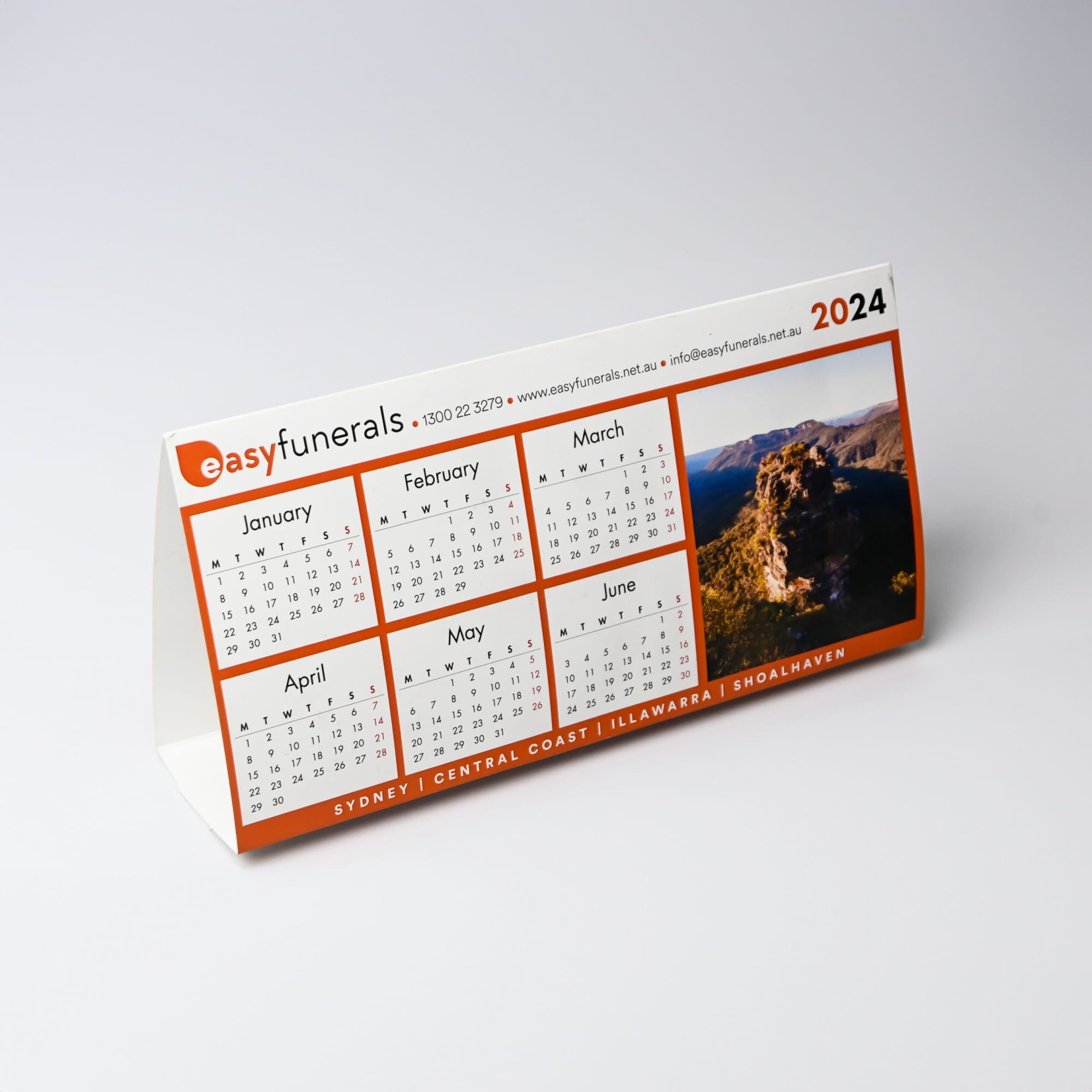 A desk calendar featuring a white and orange design with months displayed from January to June, including a scenic image.