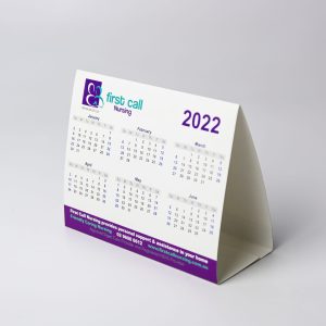 A desk calendar featuring a white background with purple accents, displaying month grids for 2022. It has a logo.