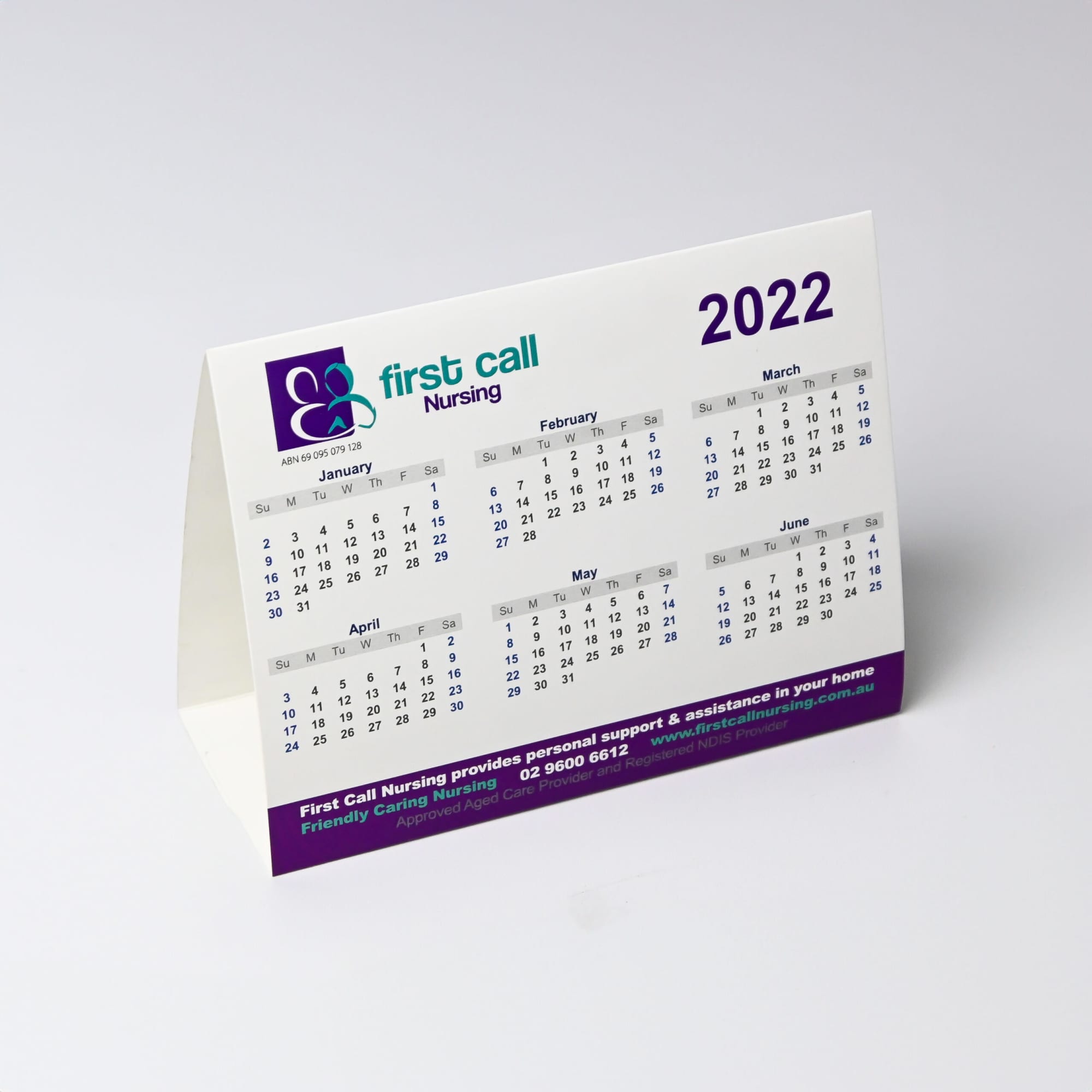 A desk calendar featuring months from January to June 2022, with a white background and purple accents. It includes a logo.