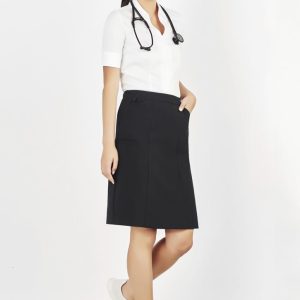A woman in a white shirt and black cargo skirt, paired with white sneakers, stands against a light background.