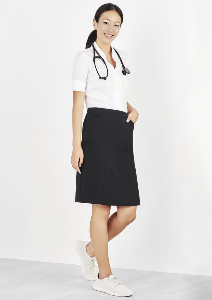 A woman in a white shirt and black cargo skirt, paired with white sneakers, stands against a light background.