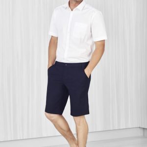 A man wearing navy cargo shorts and a white short-sleeve shirt, standing in a light-coloured setting.
