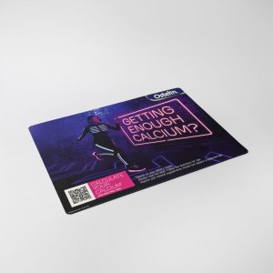 A counter mat featuring a vibrant design with a person and a logo, predominantly in dark colours.