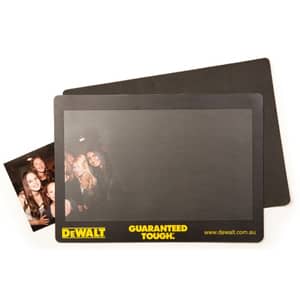 A natural rubber counter mat featuring a smooth black surface and a logo at the bottom, with a small photo included.