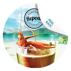 A circular coaster featuring a cocktail with a prawn and a beach background, predominantly in turquoise and orange.