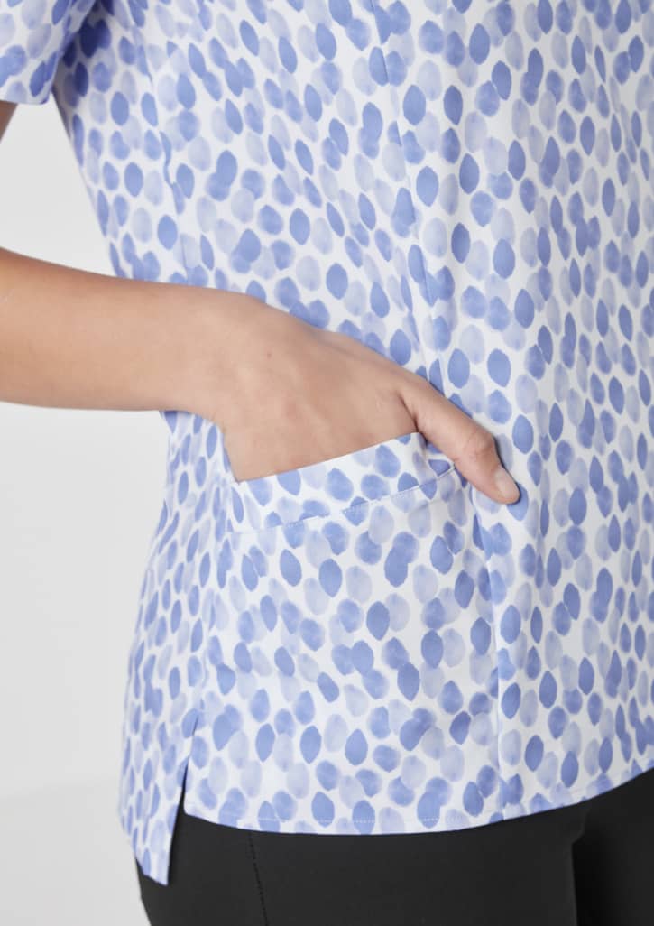 A light blue tunic with a stardust print, featuring a side pocket and short sleeves.
