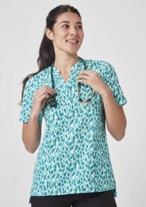 A turquoise tunic with a stardust print, featuring a collar and short sleeves, worn by a smiling woman holding a stethoscope.
