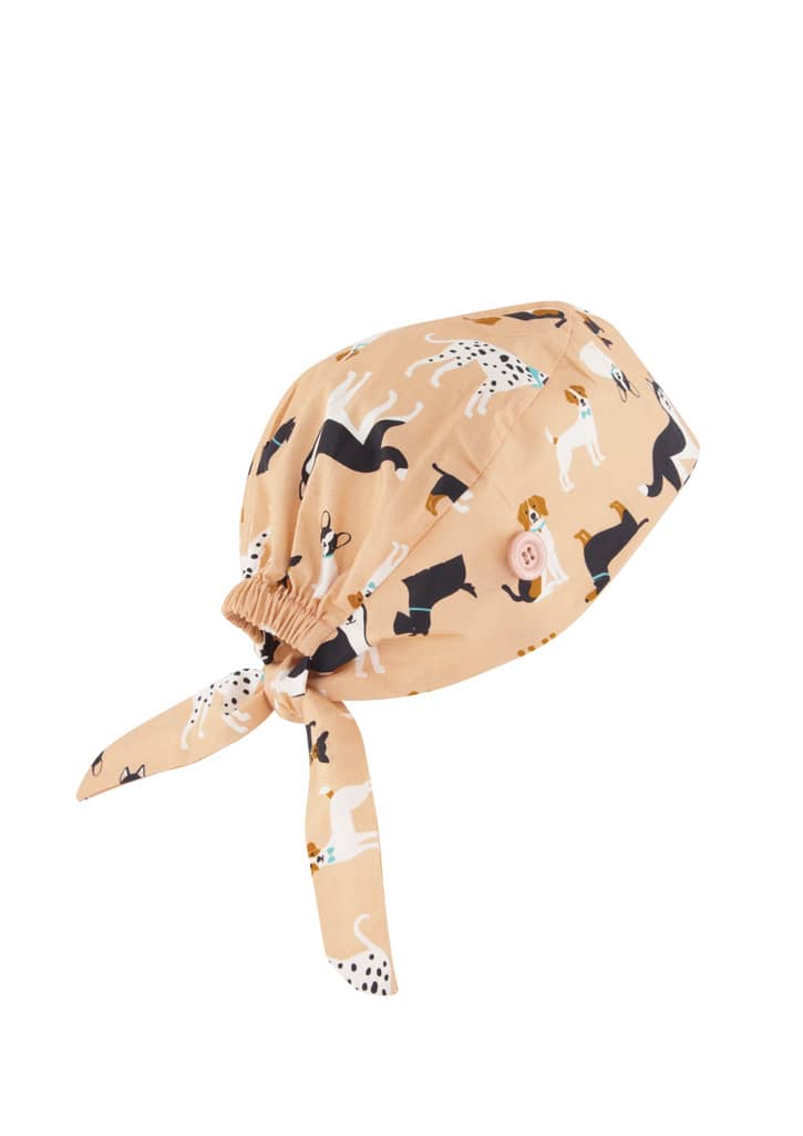 A unisex scrub cap with a beige background, decorated with various dog patterns and a tie at the back.