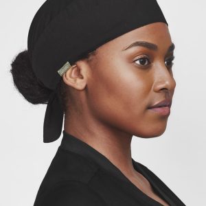 A black unisex reversible scrub cap worn by a person, featuring a logo on the side.