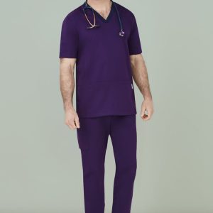 A man wears purple scrub pants with a matching scrub top and stethoscope, set against a pale background.