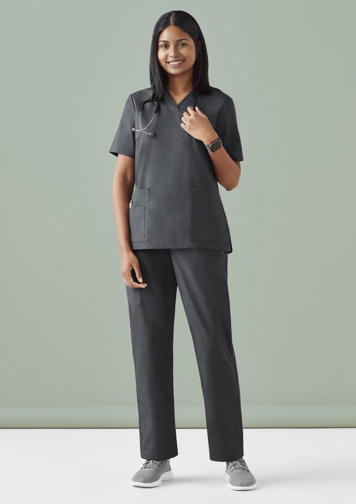 A model wearing black Women's Tokyo Scrub Pant paired with a matching top, featuring pockets and a logo.