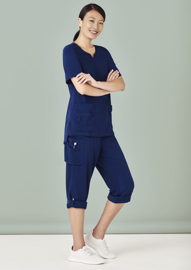 Navy women's scrub top and slim leg scrub pant, featuring pockets and a relaxed fit, set against a light green background.