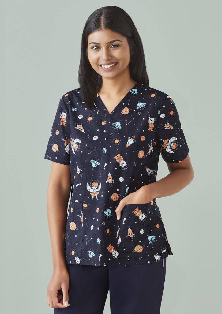 A navy scrub top featuring a playful space print with planets, astronauts, and stars. Includes a pocket and logo.