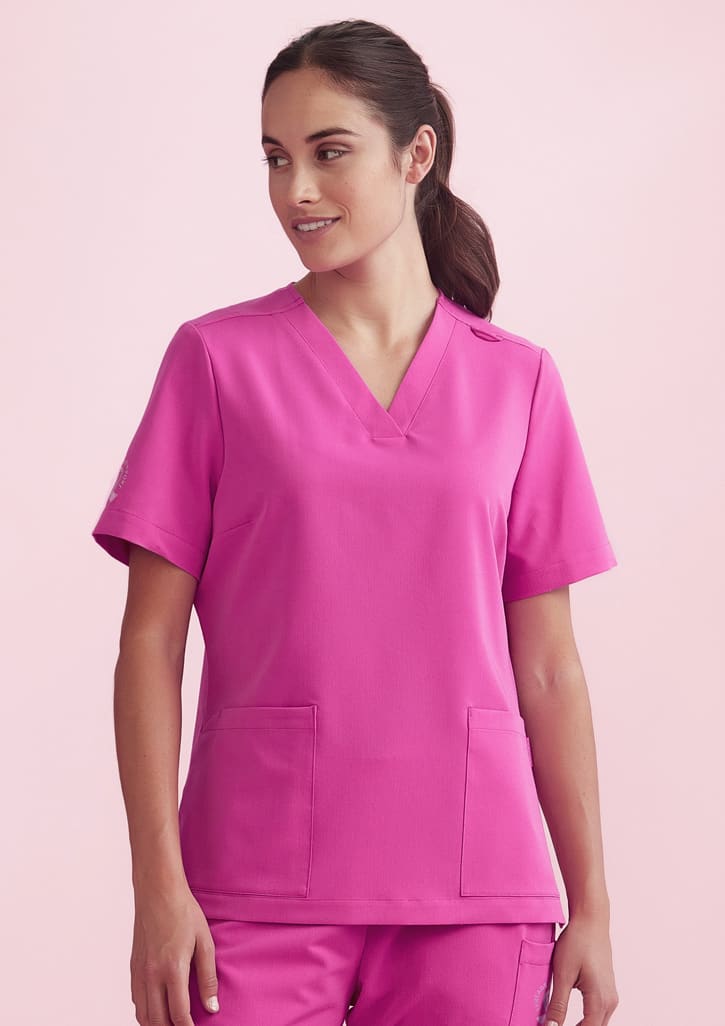 A pink women's V-neck scrub top with short sleeves and two front pockets. It features a logo on one sleeve.