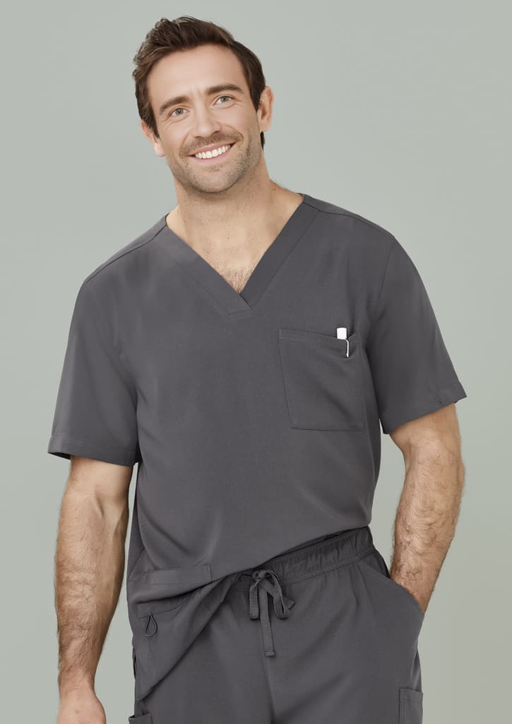 A man wearing a grey V-neck scrub top with a pocket. The scrub top features a loose fit and casual style.