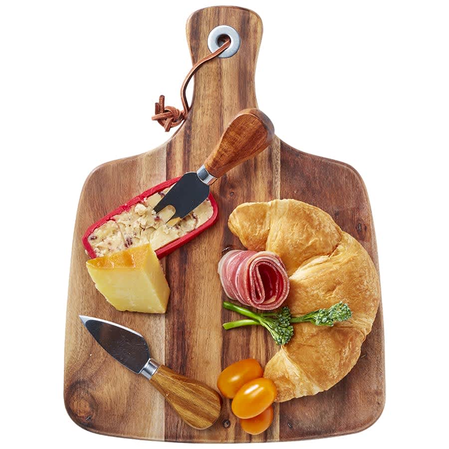 Acacia cheeseboard with knife set, featuring a wooden board, cheese, cured meats, croissant, and cherry tomatoes.
