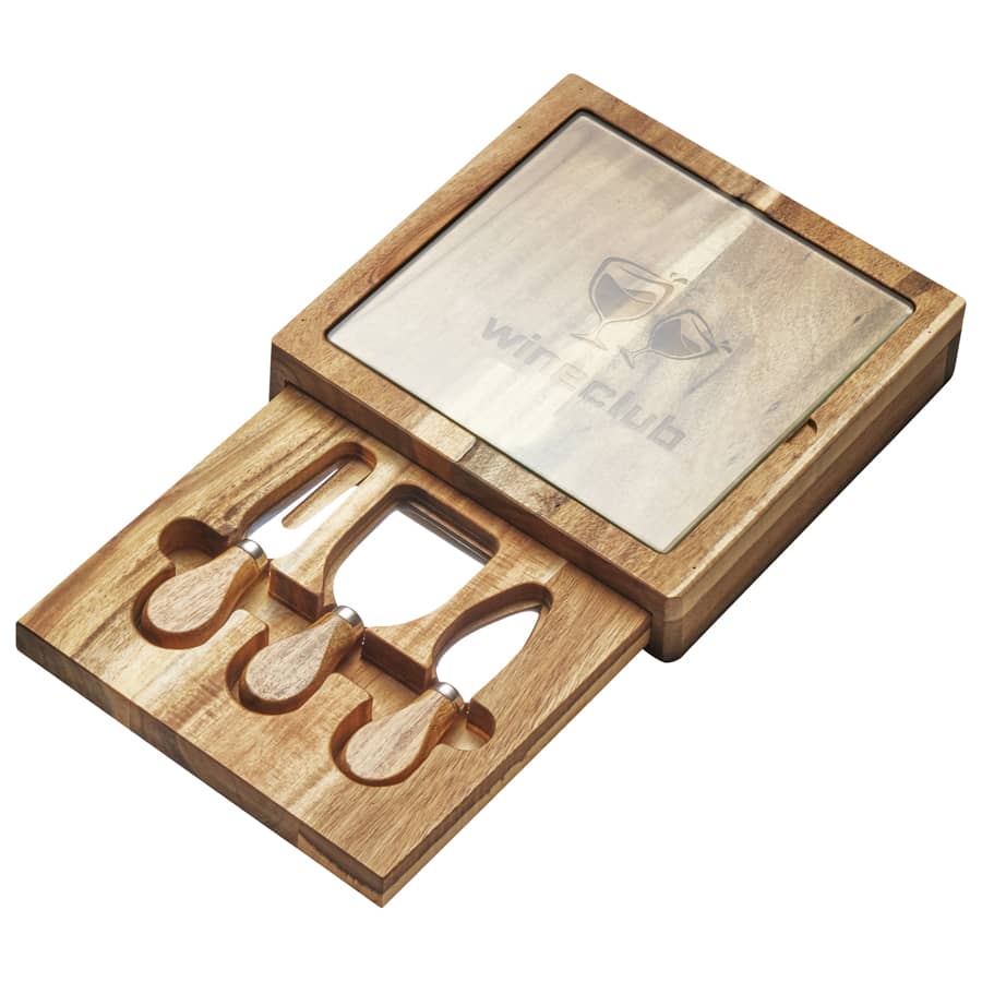 A wooden cheese board and knife set with three stainless steel tools, featuring a glass top and a logo.