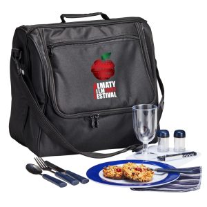 A black picnic basket set includes utensils, a drink glass, condiment containers, and a blue plate with food.