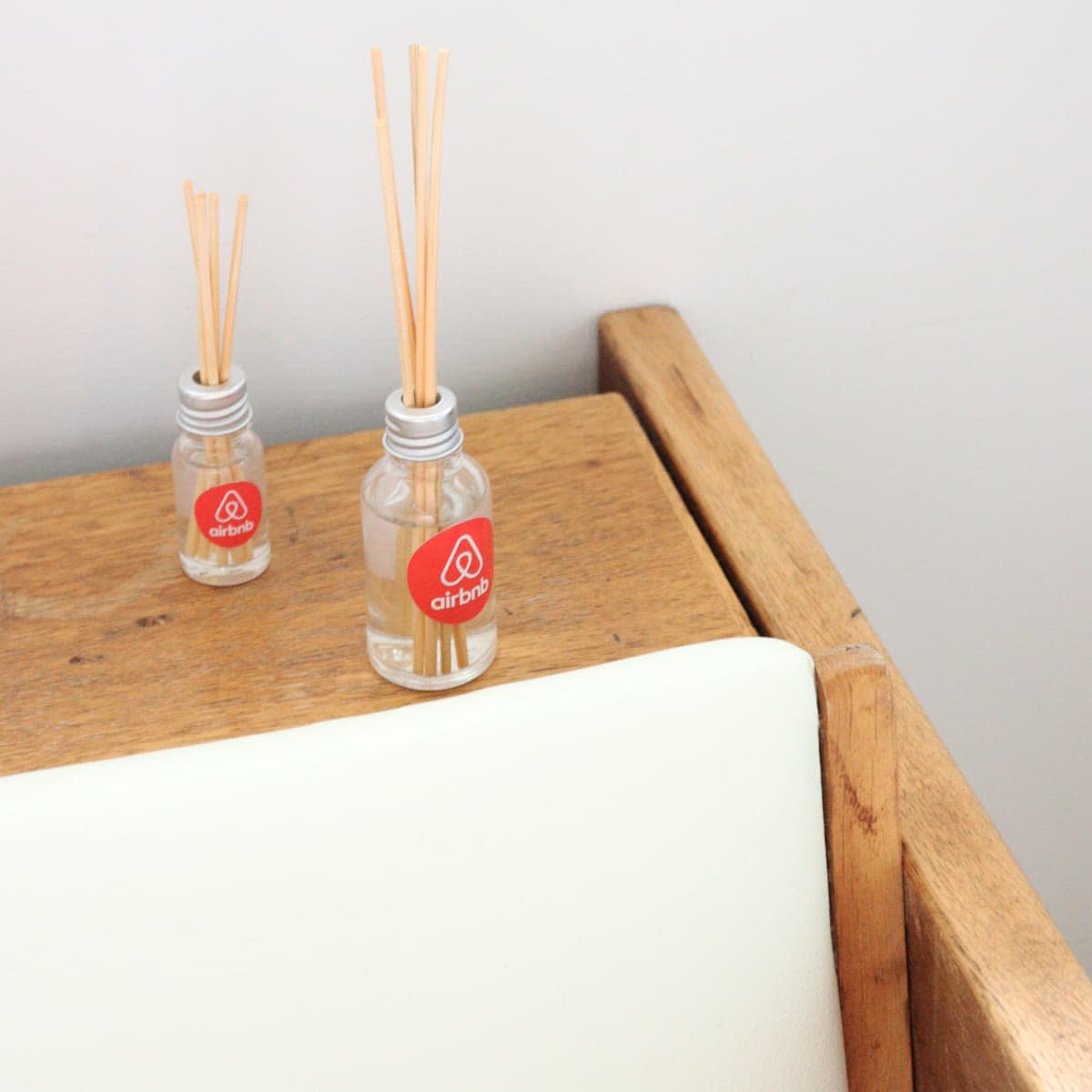 A 10ml clear glass reed diffuser with wooden sticks, positioned on a wooden surface next to a smaller similar diffuser.