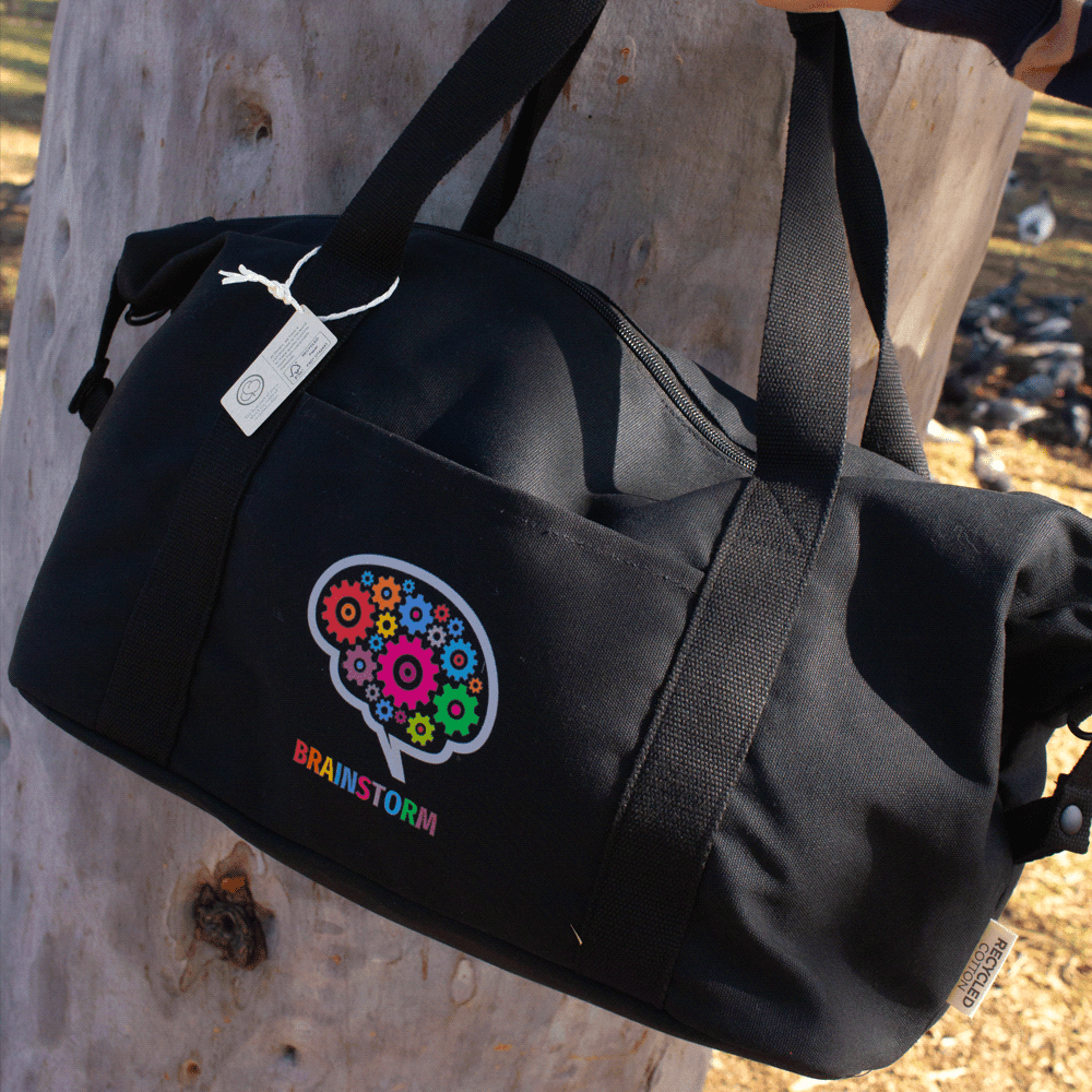 A black recycled canvas duffle bag with colourful gear and brain logo, featuring dual handles and a shoulder strap.