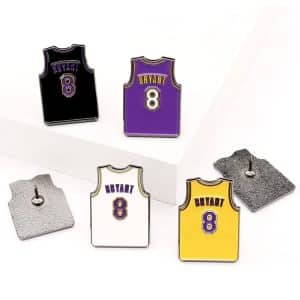 A set of lapel pins featuring basketball jerseys in purple, black, white, and yellow, each with a logo.
