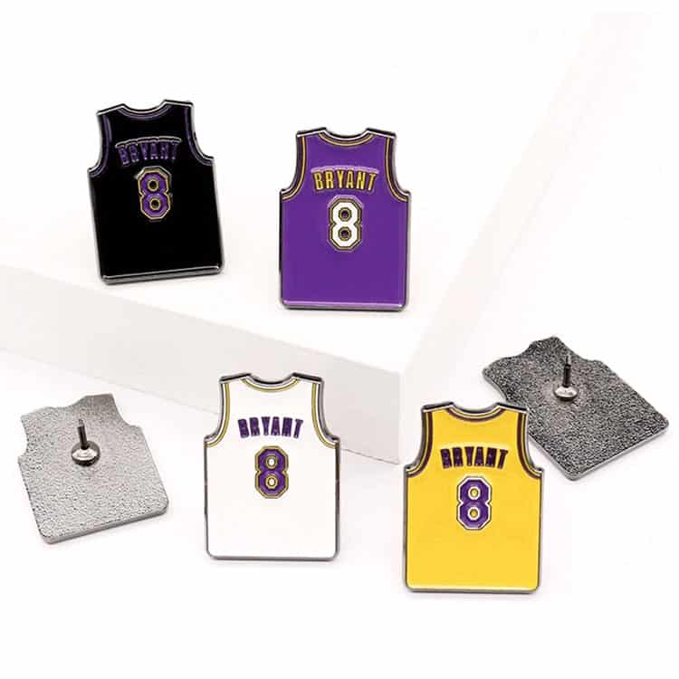 A set of lapel pins featuring basketball jerseys in purple, black, white, and yellow, each with a logo.