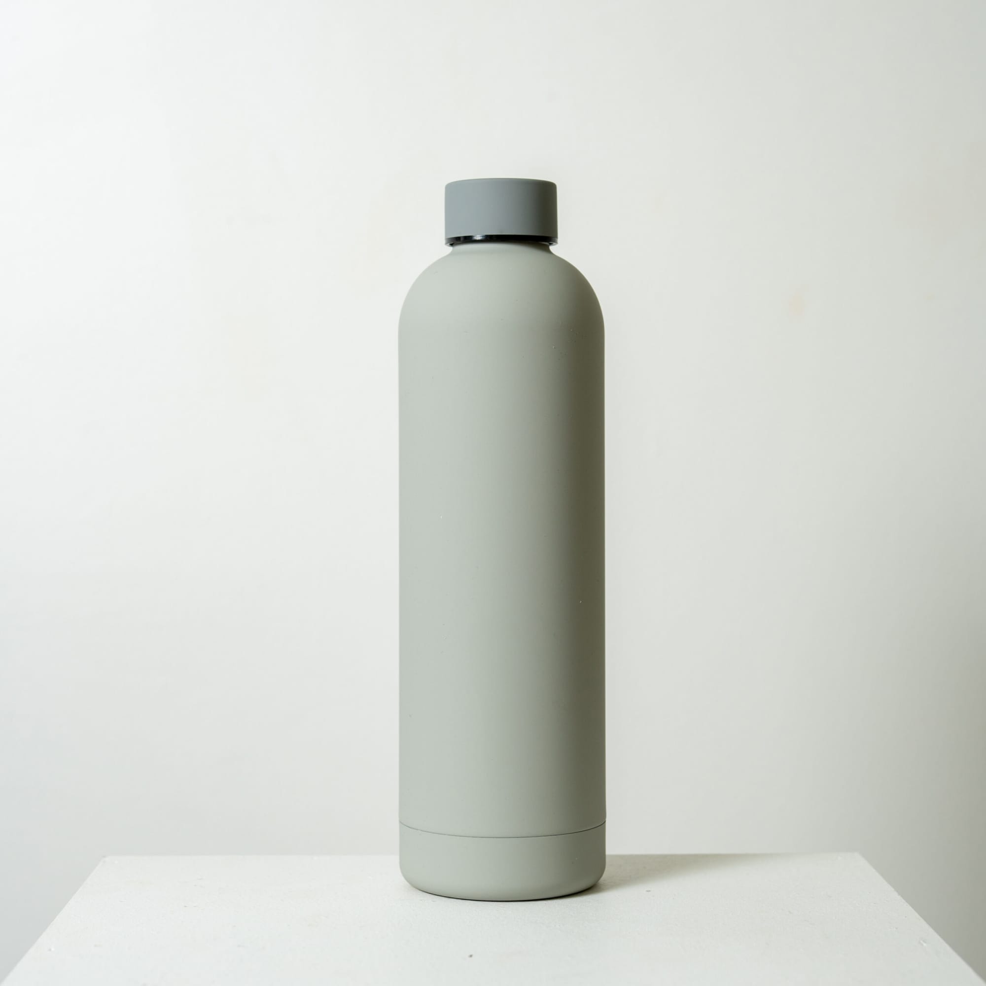 A drink bottle in matte grey with a screw-top lid and a minimalist design. It features a logo on the side.