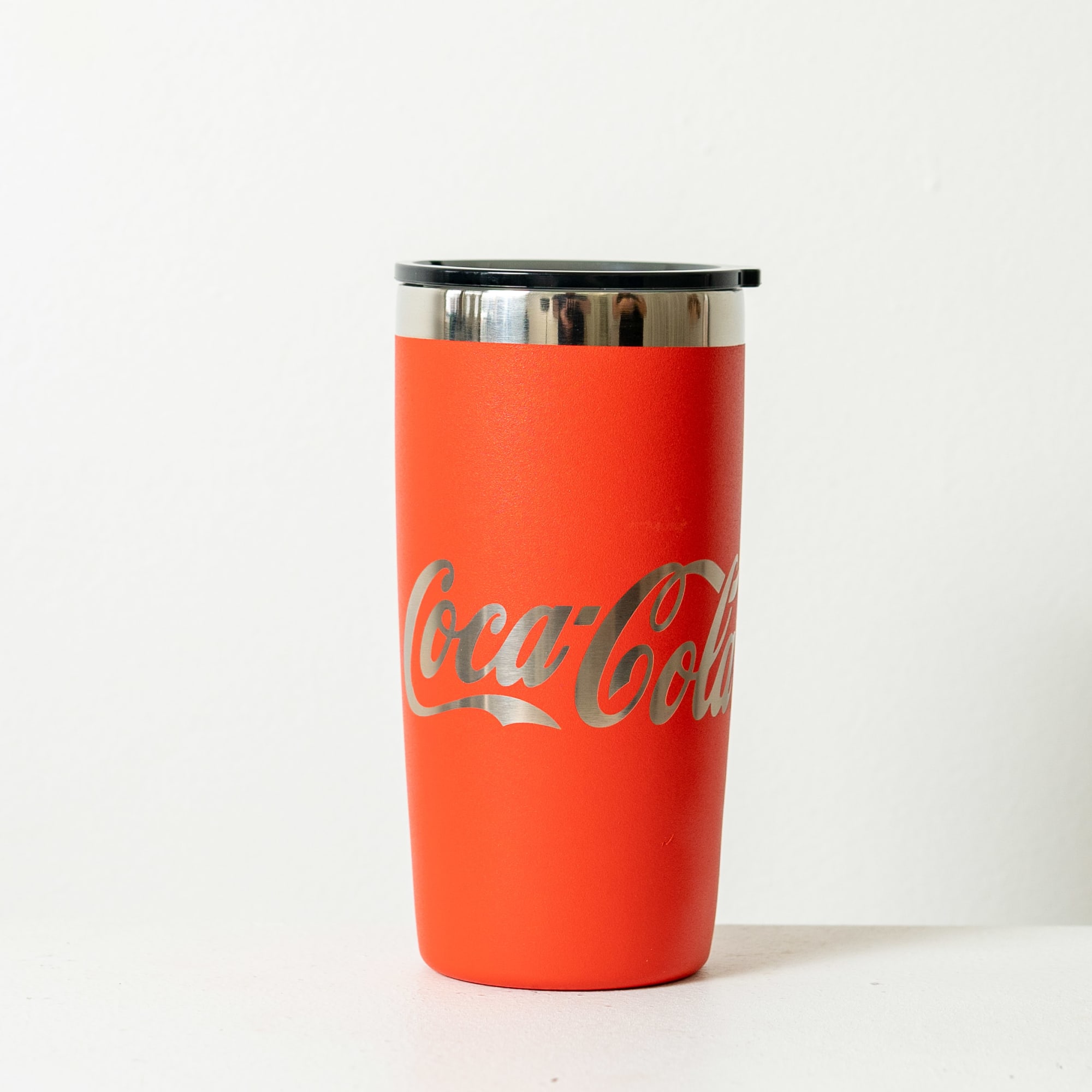 A drink bottle in a rust red colour with a stainless steel lid and a logo on the side.