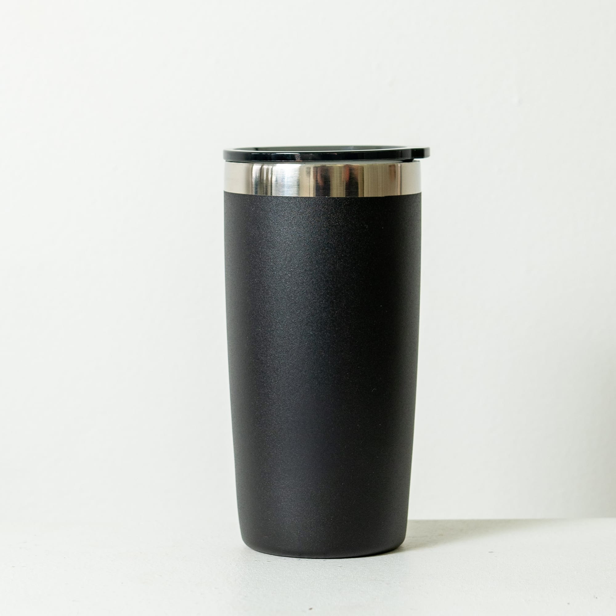 A drink bottle in a rust orange colour with a stainless steel rim and a black lid. It has a logo on the side.