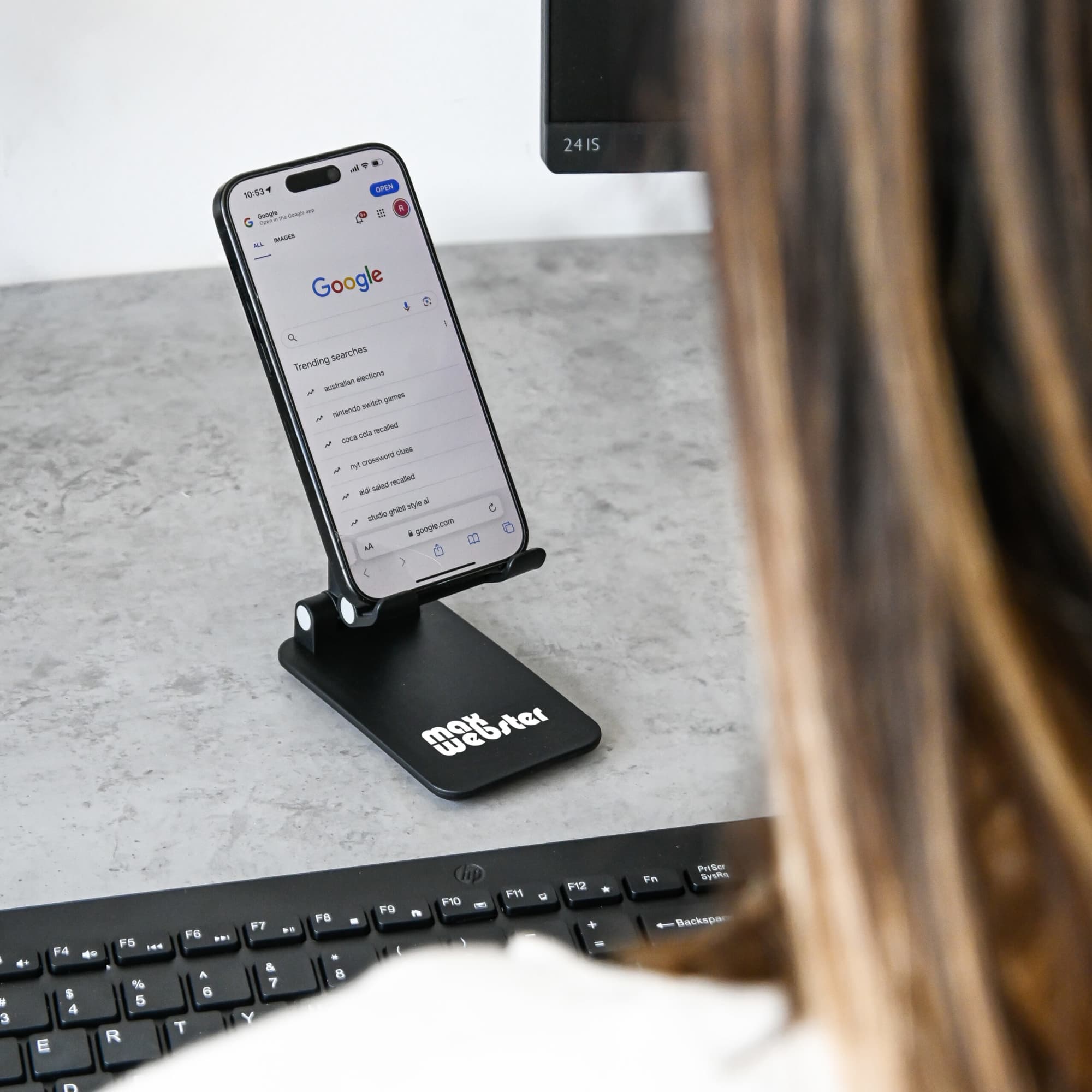A white folding desktop mobile phone and tablet stand with a textured surface.