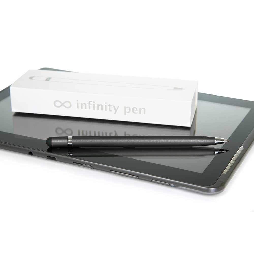 A sleek metal Infinity Pen in matte black, resting on a tablet, with its white packaging nearby.