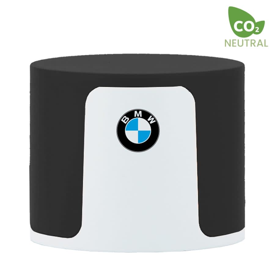 A cylindrical speaker in black and white, featuring a logo on the front and marked as CO2 neutral.