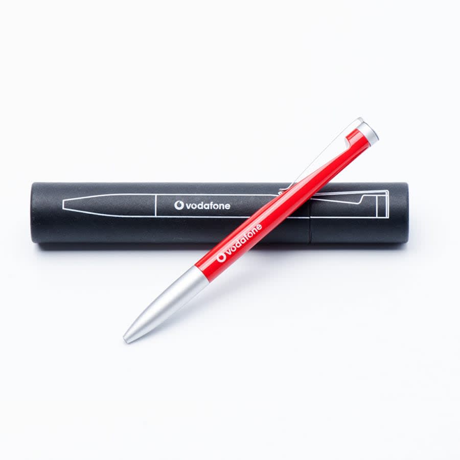 A red metal ballpoint pen with a silver tip, resting beside a black cylindrical case featuring a logo.