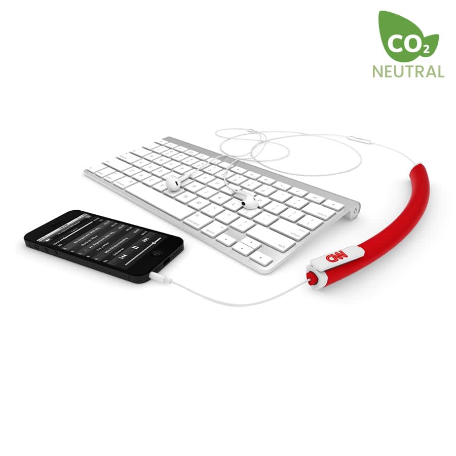 A red earbud organiser with headphones connected to a smartphone and placed beside a computer keyboard.