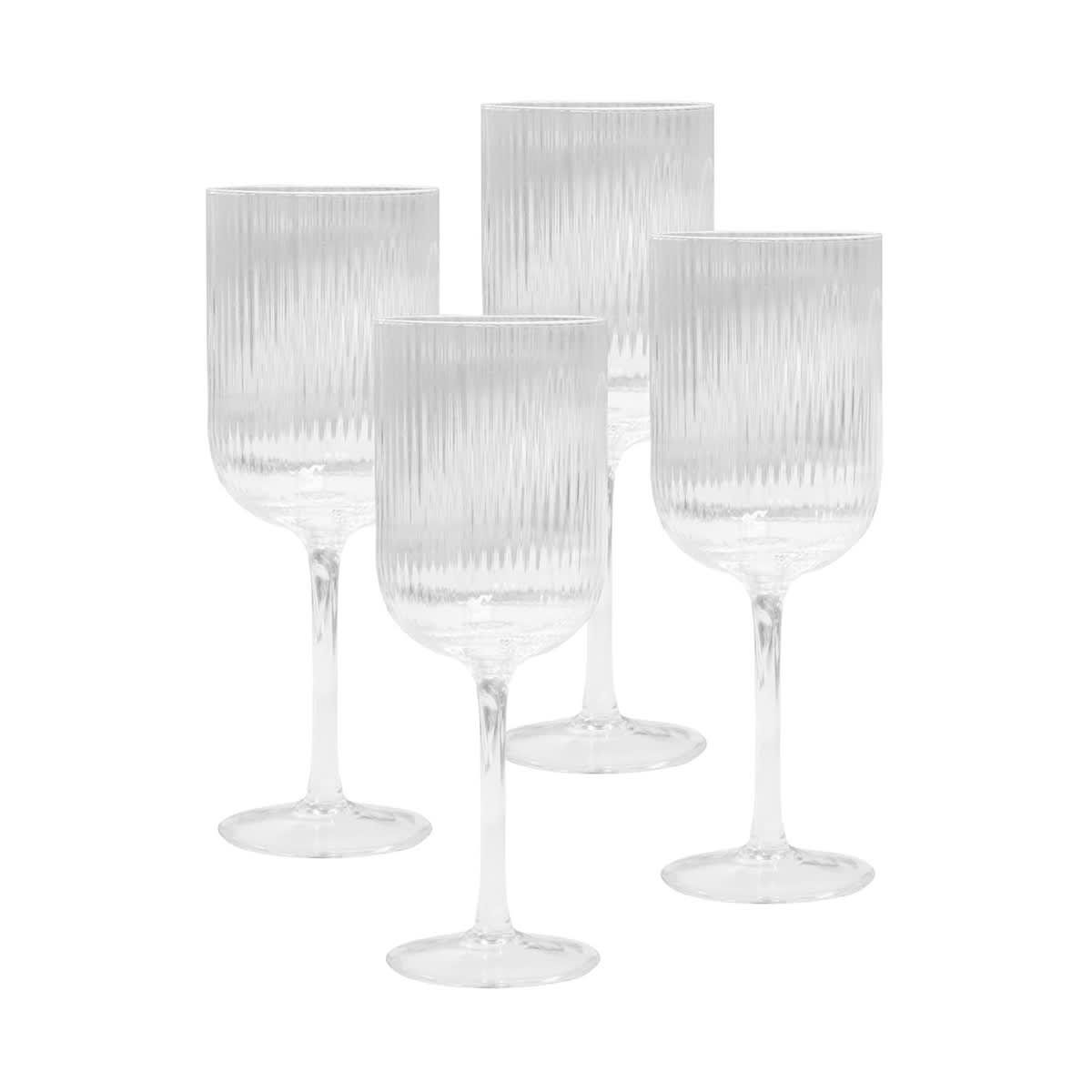 Four clear glass wine glasses with ribbed design, featuring tall stems and a minimalist aesthetic.