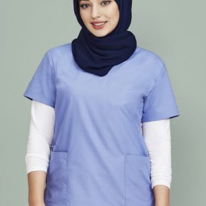 A woman wearing a light blue scrub top with two pockets, layered over a white long-sleeve shirt, and a navy hijab.