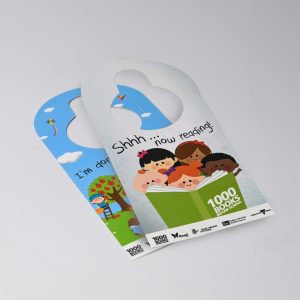 A double-sided door hanger featuring colourful illustrations of children reading and playful scenes, with a logo.
