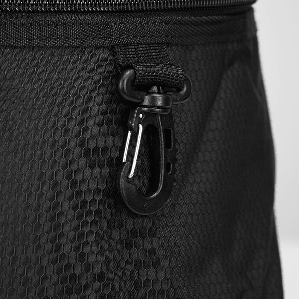 A close-up of a black duffel bag featuring a hexagonal texture and a carabiner clip attachment.