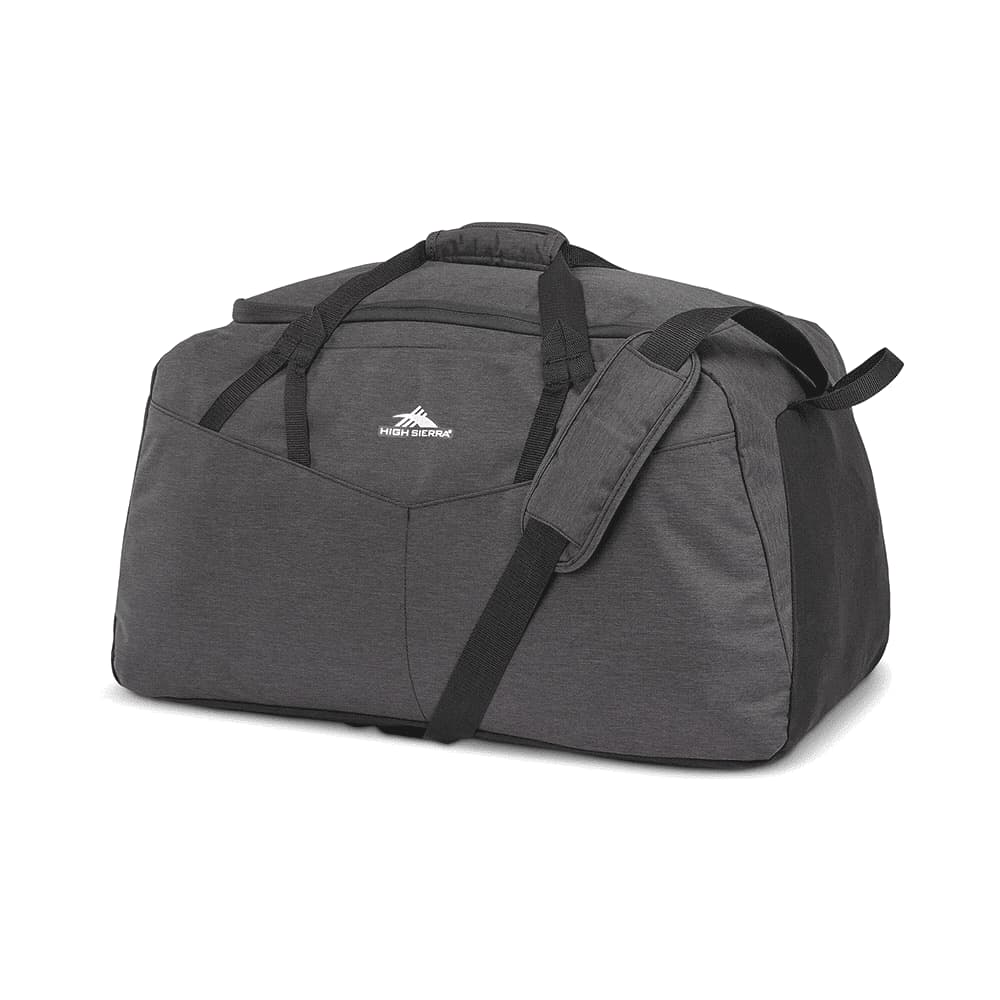 A black duffel bag with handles, held by a person standing outdoors near rocky terrain and water.