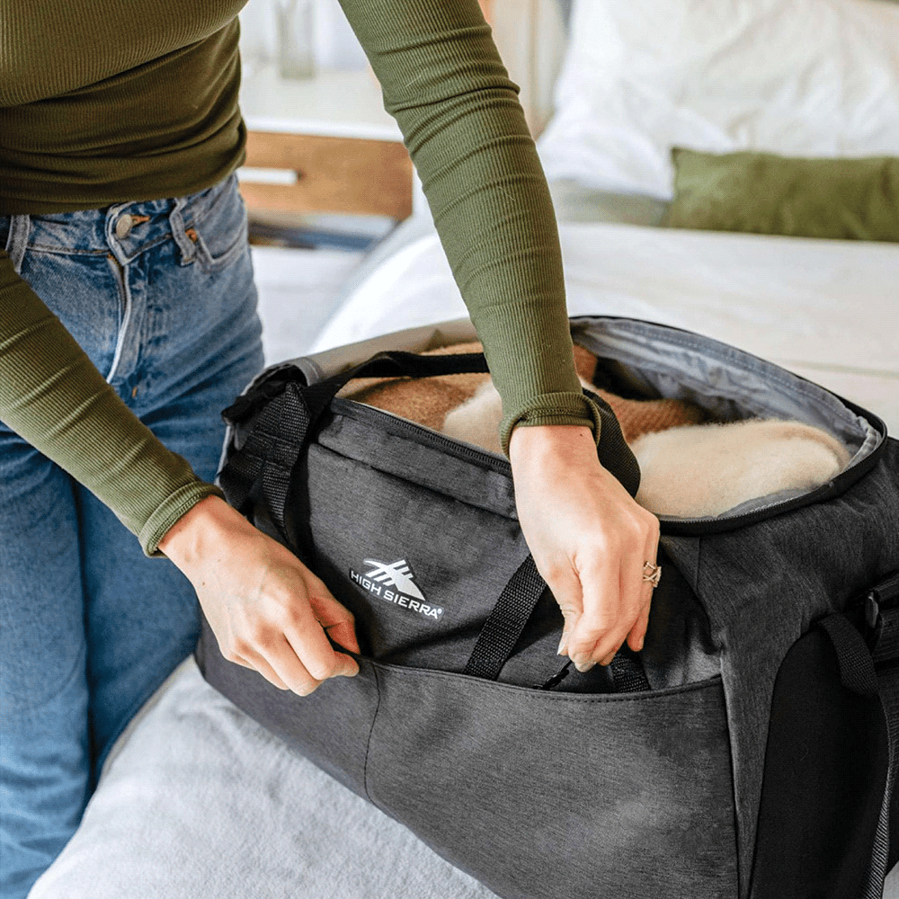 A black duffel bag with a textured finish, featuring zippers and a logo. Ideal for carrying personal items.