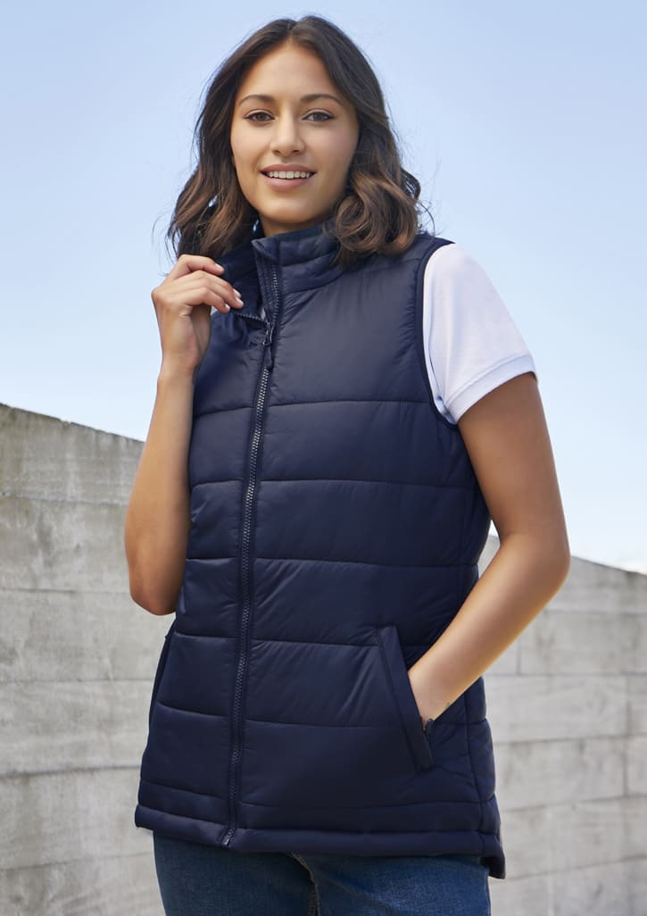 A navy women's alpine vest with a zip front, styled with a white t-shirt underneath, and featuring side pockets.