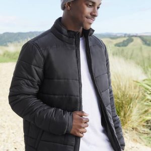 A black puffer jacket with a zip, worn by a smiling man in a grey beanie, set against a scenic outdoor background.
