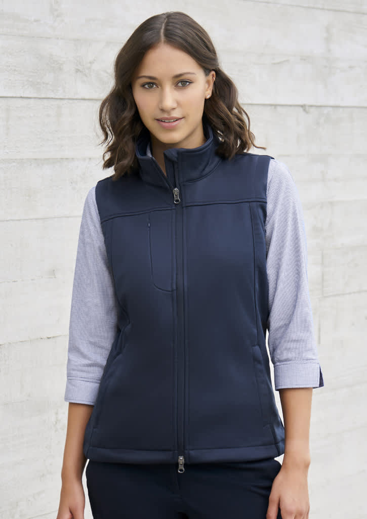 A women's softshell vest in navy blue, featuring a zip front and a high collar, with a fitted design.