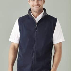 A man wearing a navy blue vest over a white shirt, displaying a stylish design with a logo on the chest.