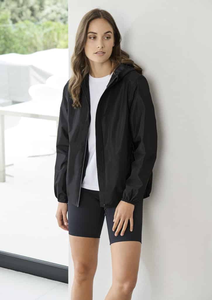 A women's black rain jacket with a hood, worn over a white shirt and black shorts, displayed indoors.