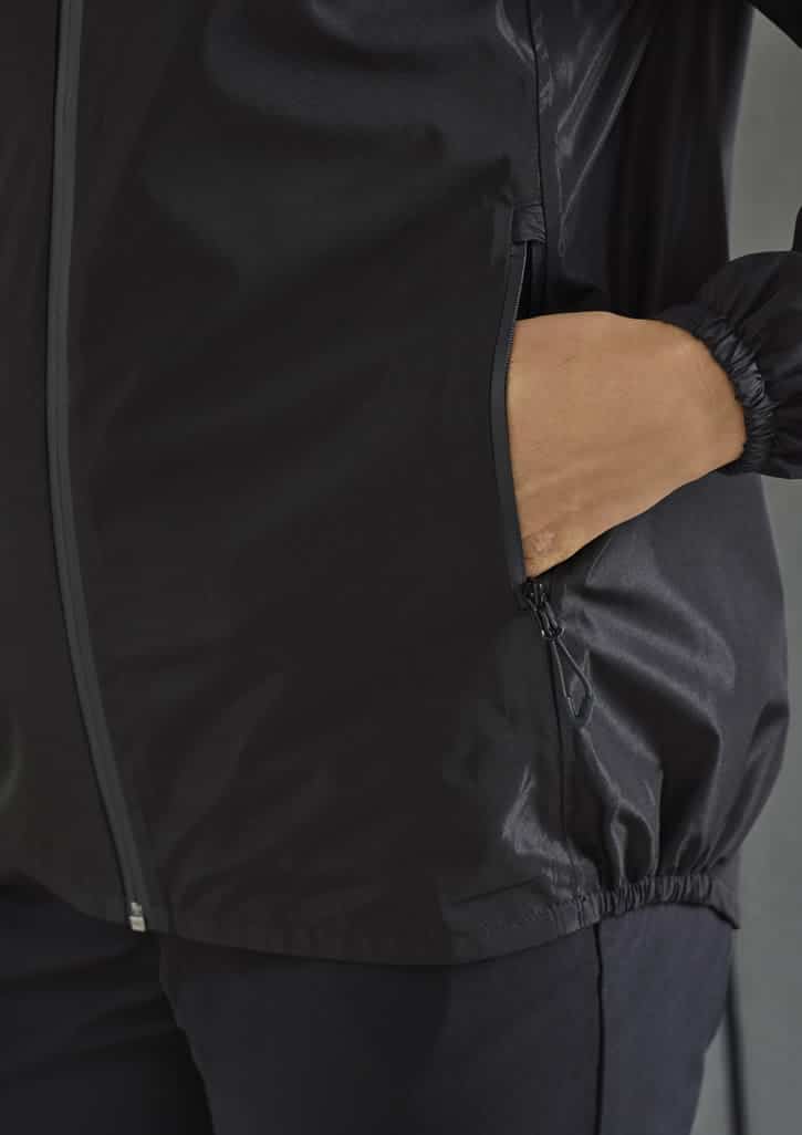 A black women's rain jacket featuring zippered pockets and elastic cuffs. It has a logo on the surface.