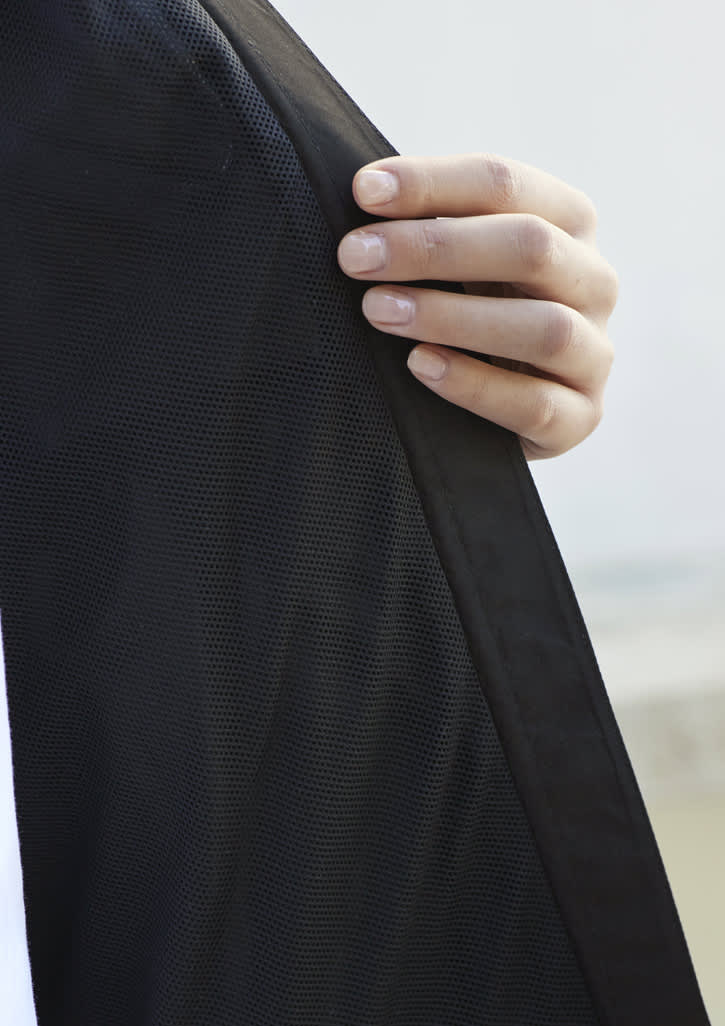 A hand holding the edge of a black women's rain jacket, showcasing the fabric texture and design details.