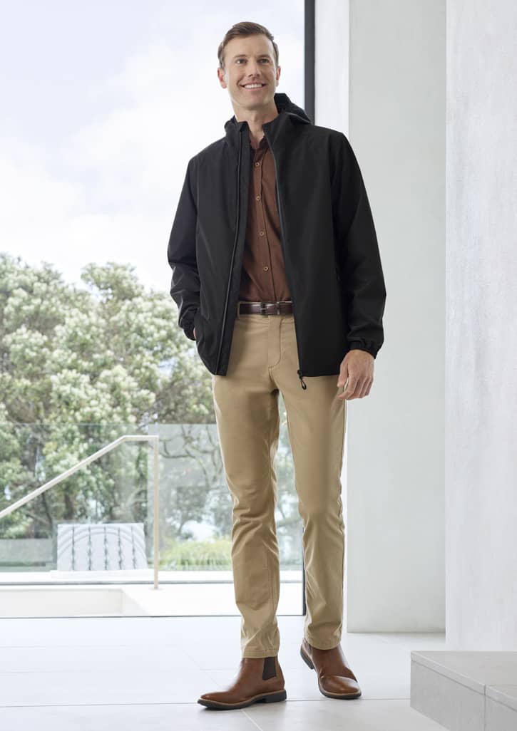 A black rain jacket with a hood, paired with a brown shirt and beige trousers, worn by a man in a modern setting.
