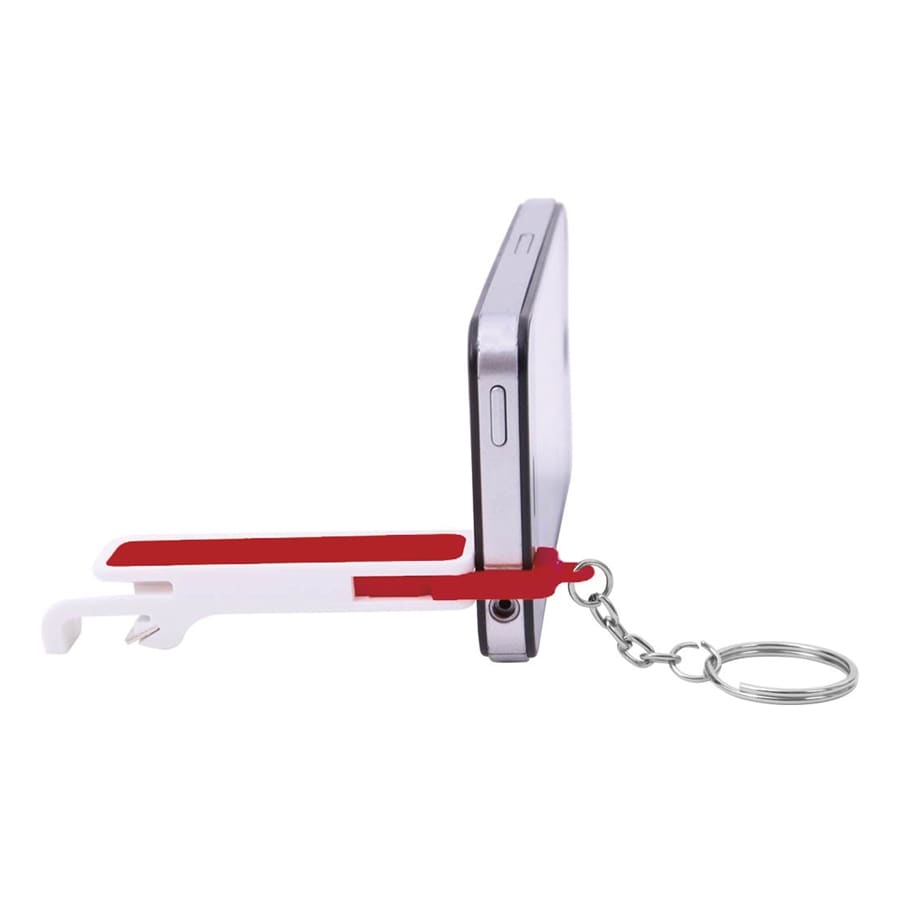 A drink bottle opener in red and white, attached to a keychain and resting against a smartphone.