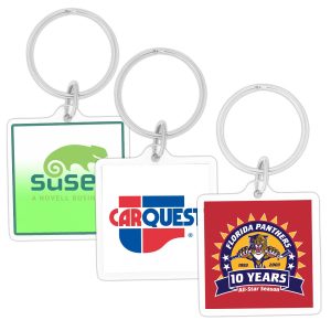 A hand holding a square acrylic keychain featuring a design in blue and white, with a logo.